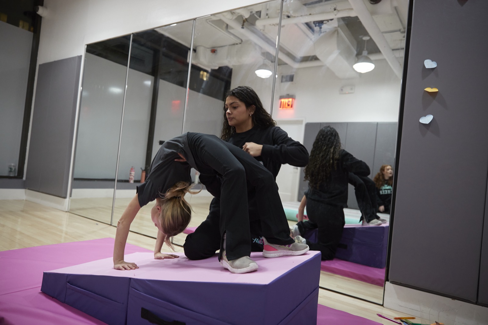 A coach guiding an athlete through a tumbling drill
